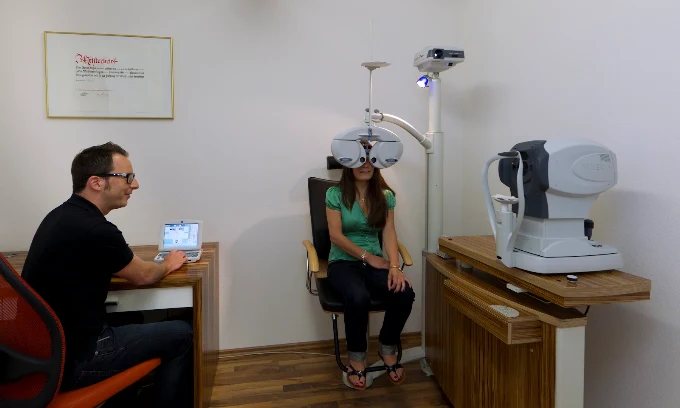 Sehtest im Optikhaus: Augenoptiker am Messplatz, Kundin am Messgerät