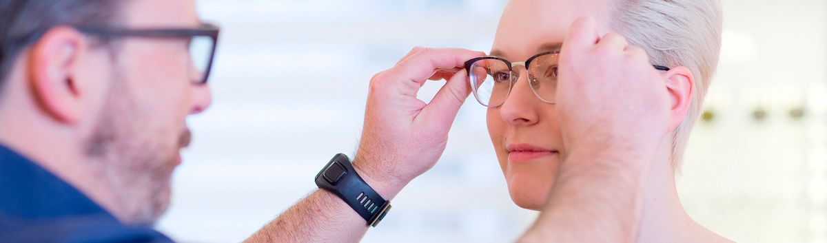 Augenoptiker passt einer Kundin eine Brille an